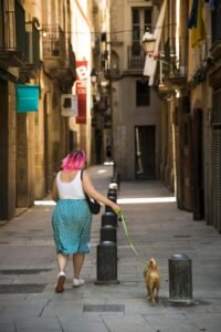 Woman with bright hair walking dog on street